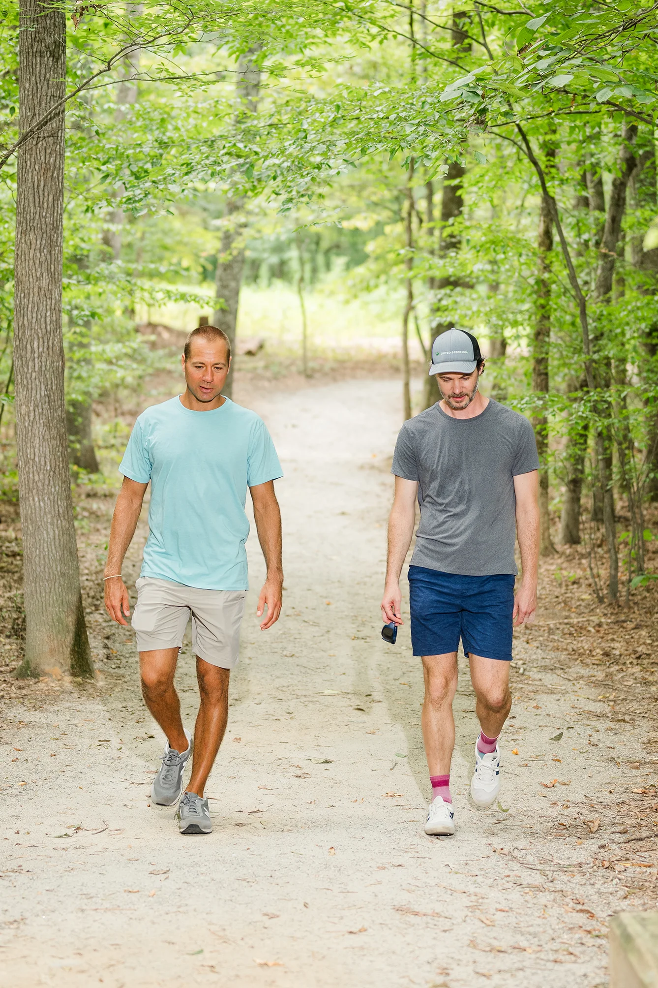 Two men walking together on a wooded trail during a walk and talk therapy session in Richmond, VA